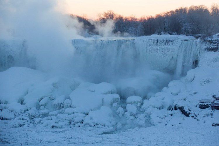 Uap muncul Air Terjun Niagara sebelum matahari terbit di, Ontario, Kanada, Kamis (31/1/2019). Cuaca ekstrem membuat sebagian Air Terjun Niagara membeku. (AFP/Lars Hagberg/kompas)

