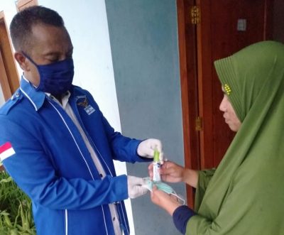 Seorang kader Partai Demokrat KBB saat memberikan masker dan hand sanitizer kepada warga. (Foto: Istimewa)