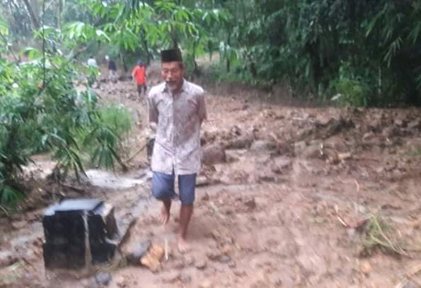 Seorang warga berjalan di atas material longsor yang masih tersisa di Desa Karangnunggal, Kecamatan Cibeber, Kabupaten Cianjur, Jawa Barat, Senin (23/3/2020). (Foto: Purwanda/istimewa)