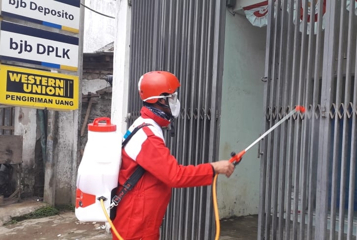 Seorang personel PMI KBB melakukan penyemprotan cairan disinfektran di salah satu ruko di pasar tradisional yang ada di KBB, Jawa Barat, Kamis (26/3/2020). (Foto: Muhammad Zein/dara.co.id)