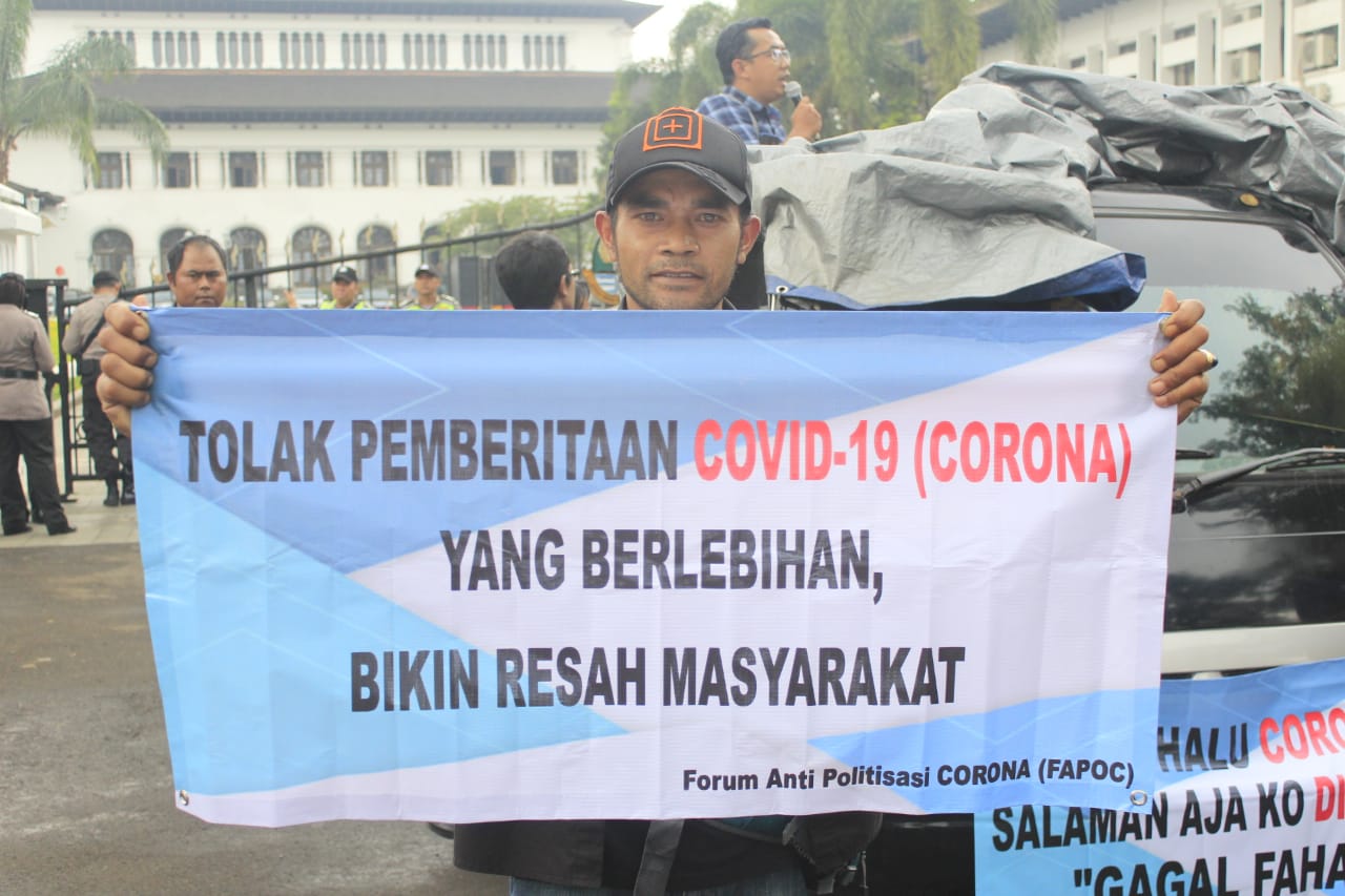 Seorang pendemo dari Forum Anti Politisasi Corona menunjukkan spanduk penolakan saat aksi di depan Gedung Sate, Jalan Diponegoro, Kota Bandung, Kamis (12/3/2020). (Foto: Ardian Resco/dara.co.id)