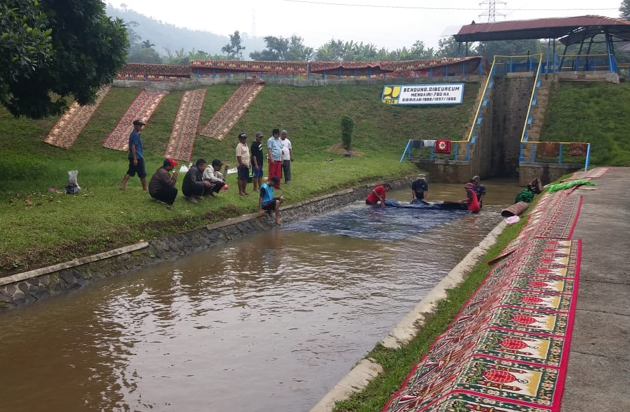 Sejumlah pengurus DKM Al Huda mencuci karpet di Bendung Cibeureum, Jalan Raya Soreang-Ciwidey, Kampung Sungapan, Desa Sadu, Kecamatan Soreang, Kabupaten Bandung, Jawa Barat, Senin (23/3/2020). (Foto: Muhammad Zein/dara.co.id)