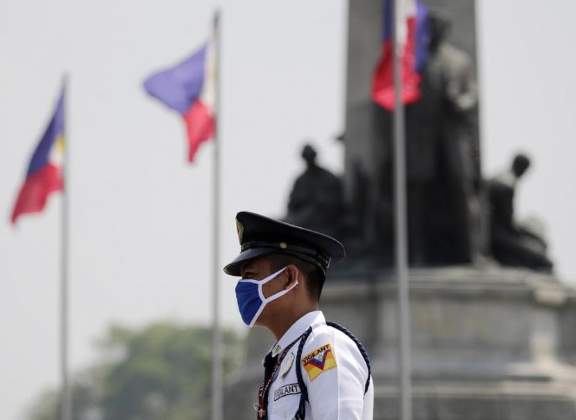 Seorang petugas dengan menggunakan masker berjaga-jaga di Kota Manila yang memberlakukan jam malam (Foto ilustrasi : republika)