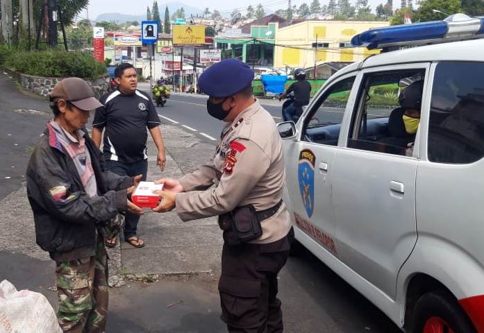 Personel Sat Brimob Yon B Pelopor saat mendistribusikan ratusan nasi boks dan masker kepada warga di wilayah Cipanas, Kabupaten Cianjur, Jawa Barat, Rabu (22/4/2020). (Foto: Angga Purwanda/dara.co.id) 