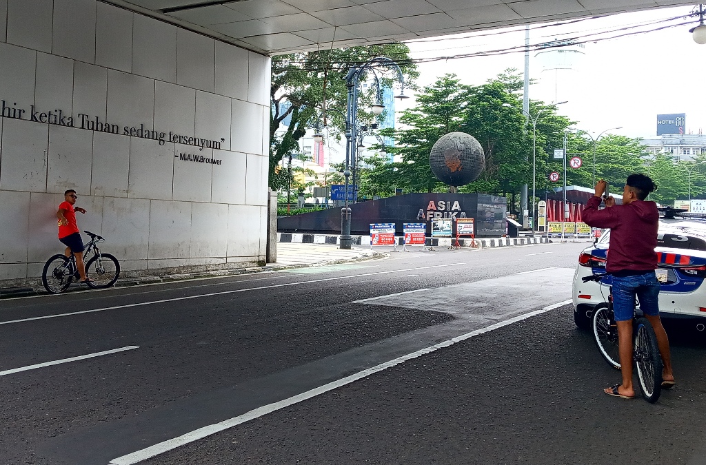 Dua orang warga saat berswafoto memanfaatkan kosongnya Jalan Asia Afrika, Kota Bandung, Jawa Barat, Senin (20/4/2020). (Foto: Ardiansyah Putra)