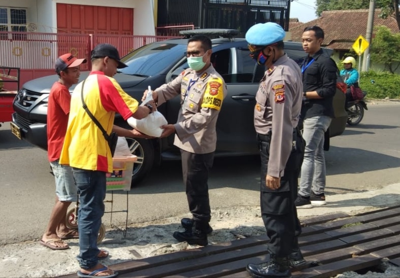 Kapolresta Bandung, Kombes Pol Hendra Kurniawan saat membagikan sembako kepada pedagang dan warga pejalan kaki di sekitar Jalan Raya Soreang, Kabupaten Bandung, Jawa Barat, Selasa (14/4/2020). (Foto: Muhammad Zein/dara.co.id)