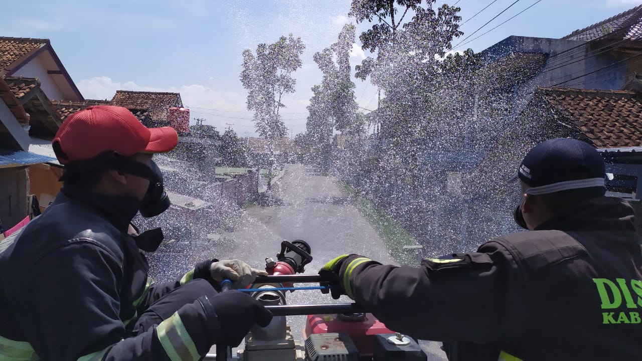 Dua orang petugas Disdamkar menyemprotkan cairan disinfektan dari atas mobil Damkar di wilayah Kecamatan Margaasih, Kabupaten Bandung, Jawa Barat, Kamis (14/5/2020). (Foto: Pusdalops Disdamkar Kabupaten Bandung)