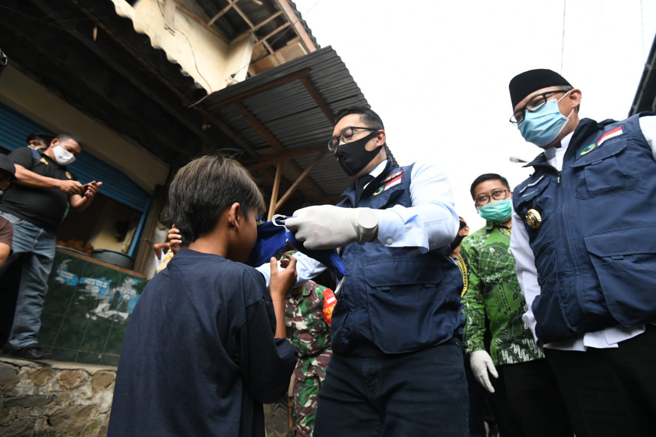 Gubernur Jabar Ridwan Kamil memasangkan masker kepada seorang anak saat mengunjungi Pasar Cisarua, Kecamatan Cisarua, Kabupaten Bogor, Jawa Barat, beberapa waktu lalu. (Foto: Humas Pemprov Jabar)