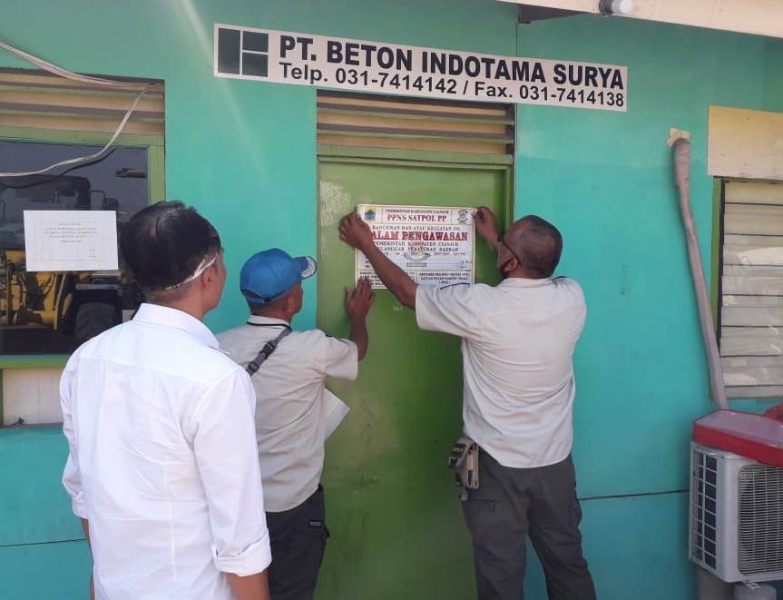 Anggota Satpol PP saat menempelkan stiker penyegelan di salah satu pintu perusahaan batching plan di Kabupaten Cianjur, Jawa Barat, Rabu (29/7/2020). (Foto: Angga Purwanda/dara.co.id)