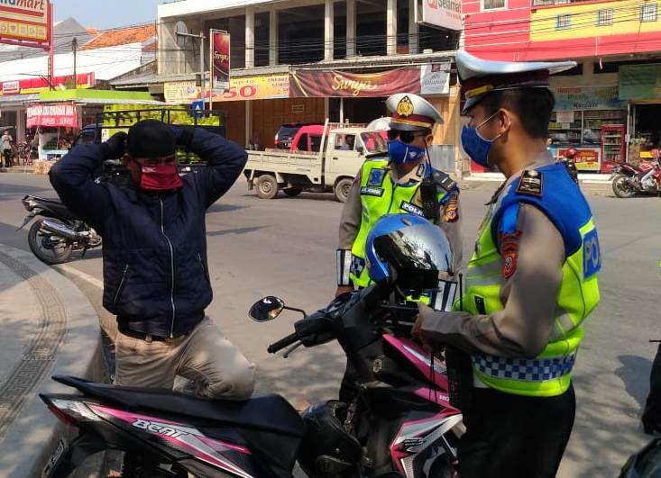 Seorang pengendara memasangkan masker yang diberikan oleh para anggota Satlantas Polres Cianjur bersamaan dengan kegiatan Operasi Patuh Lodaya 2020, beberapa waktu lalu. (Foto: Angga Purwanda/dara.co.id)