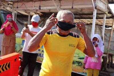 Seorang warga Desa Trusmi Wetan, Kecamatan Plered, Kabupaten Cirebon, Jawa Barat, memasangkan masker saat akan menjalani pemeriksaan kesehatan, Selasa (28/7/2020). (Foto: Humas Pemkab Cirebon)