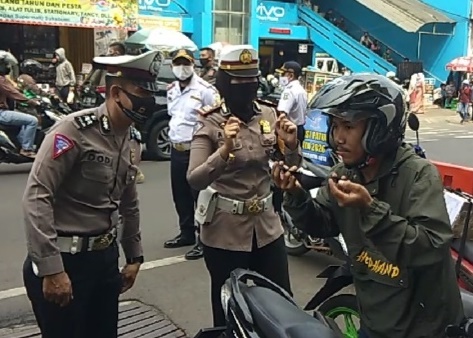 Dua orang anggota Polres Sukabumi Kota meminta kepada seorang pengendara untuk memakai masker pada hari pertama Operasi Patuh Lodaya 2020 di Jalan Ahmad Yani, Kota Sukabumi, Jawa Barat, Kamis (23/7/2020). (Foto: Riri Satiri/dara.co.id)