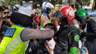 Seorang Polwan memakaikan masker kepada bocah salah seorang pengguna jalan (Foto : vera/dara.co.id)