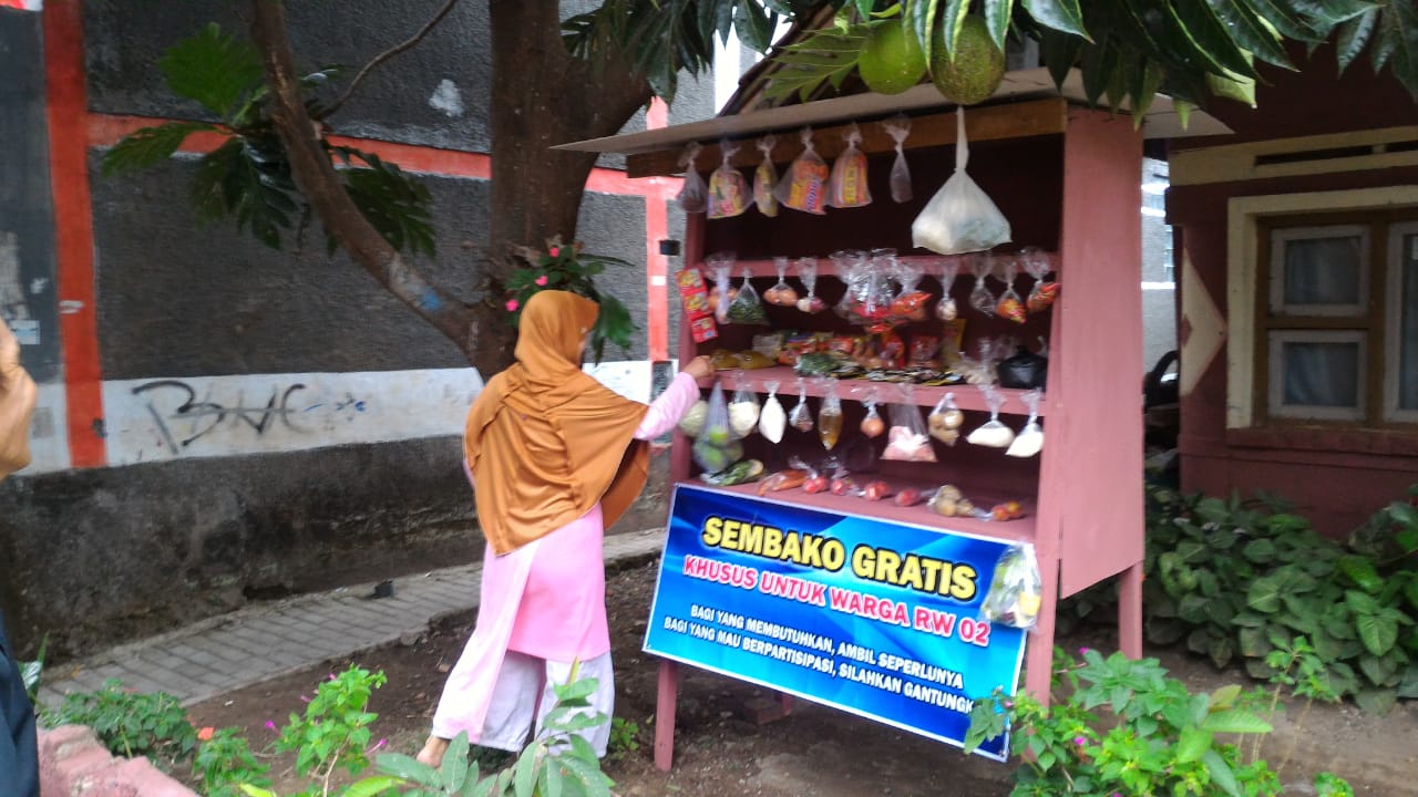 Seorang Ibu mengambil salah satu kebutuhan sembako yang digantung di ATM Sembako Gratis milik RW 02 Kelurahan Sukakarya, Kecamatan Tarogong Kidul, Kabupaten Garut (Foto: Adnre/dara.co.id)