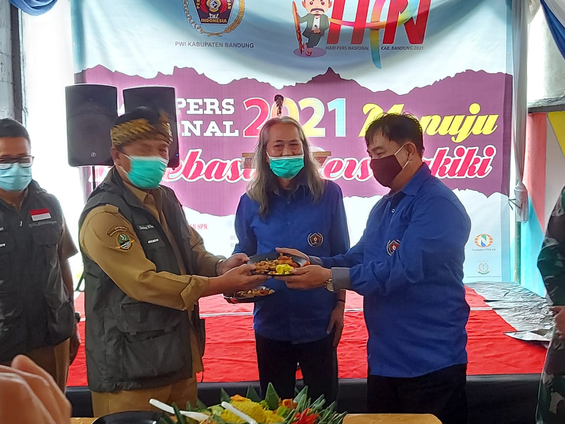 Bupati Bandung Dadang M Naser, disaksikan Ketua PWI Kabupaten Bandung Rahmat Sudarmaji memberikan potongan tumpeng kepada  seorang wartawan, pada Puncak Hari Pers Nasional Tingkat Kabupaten Bandung, Selasa, (9/2/2021)