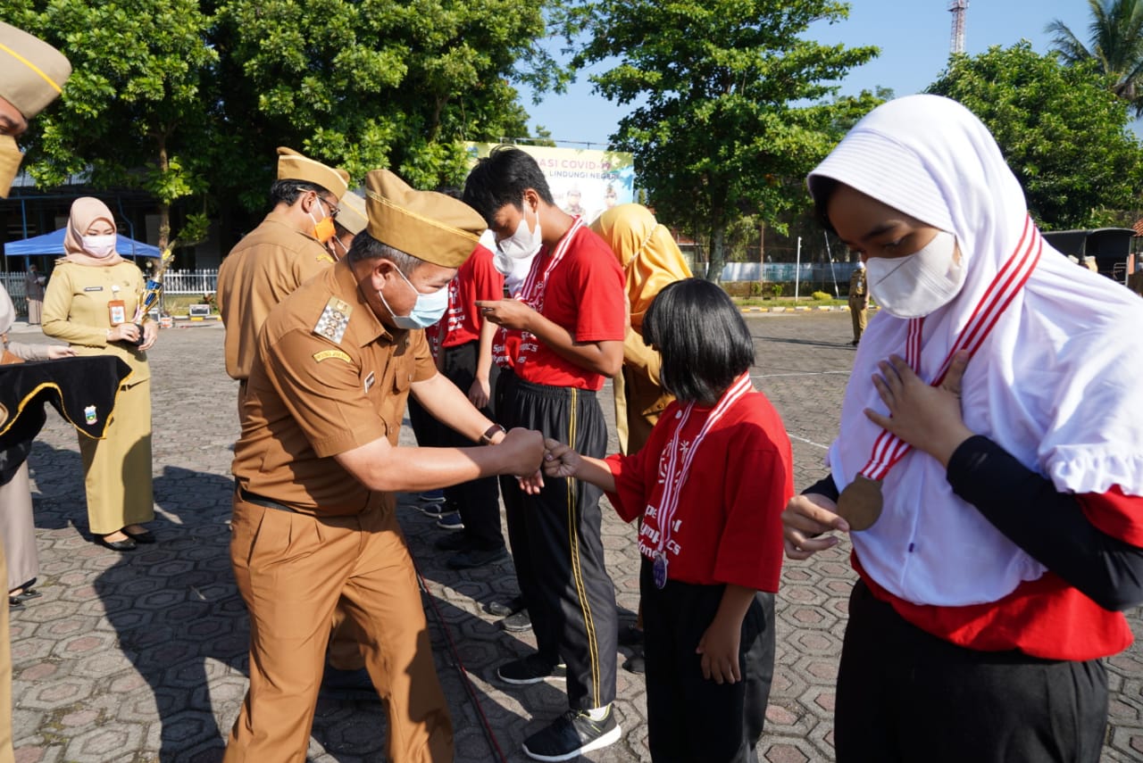 Bupati Garut, Rudy Gunawan, mengalungkan medali kepada kontingen Kabupaten Garut yang telah meraih prestasi pada Virtual Special Olympic Indonesia (SOIna)Tingkat Nasional Tahun 2020 di Lapang Setda Kabupaten Garut, Senin (26/4/2021) (Foto: Istimewa)