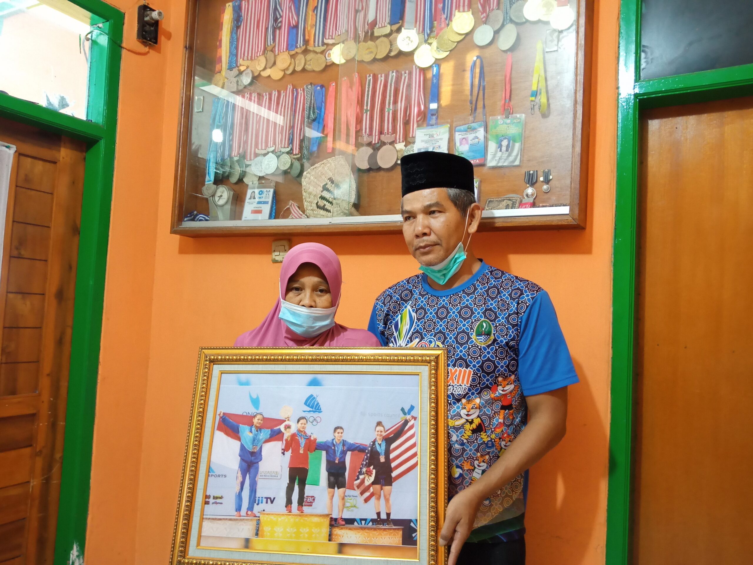 
Siti Aisyah dan suami, Kedua orangtua Windy Cantika Aisyah perain perunggu di Olimpiade Tokyo 2020, untuk kontingen Indonesia memperlihatkan foto anaknya saat meraih prestasi di cabang olahraga angkat besi. (Foto: verawati/dara.co.id)
