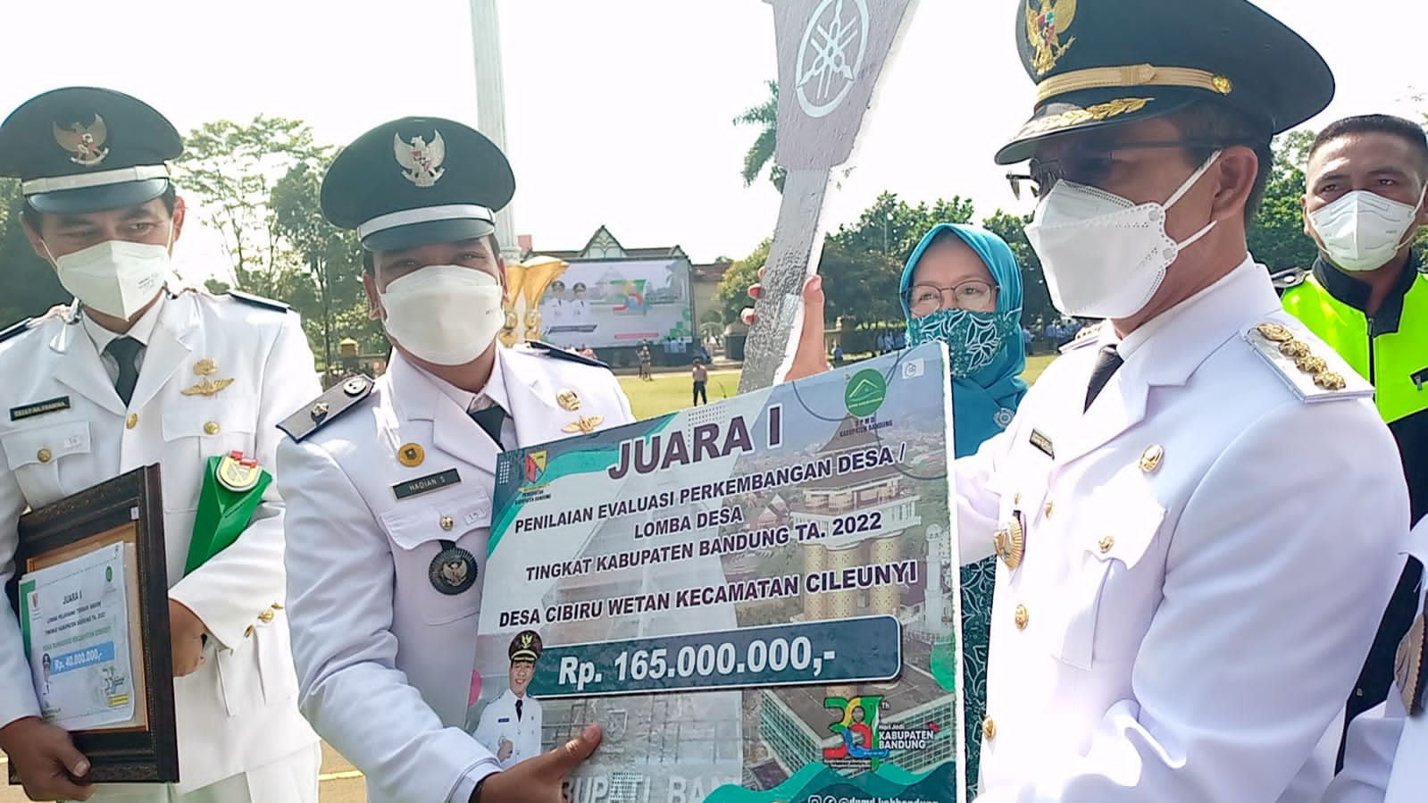 Bupati Bandung Dadang Supriatna (kanan) menyerahkan hadiah kepada Kades Cibiruwetan Hadian Supriatna yang berhasil meraih juara I lomba desa se Kab. Bandung di sela-sela peringatan HUT ke-381 Kab. Bandung, di Lapangan Upakarti Soreang, Rabu (20/4/2022) (Foto: Istimewa)