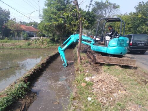 Alat berat backhoe sedang melaksanakan pengerjaan pengerukan endapan lumpur di selokan Jalan Raya Solokanjeruk-Majalaya Desa/Kecamatan Solokanjeruk Kabupaten Bandung, Sabtu (4/6/2022). (Foto Trinata/dara.co.id)