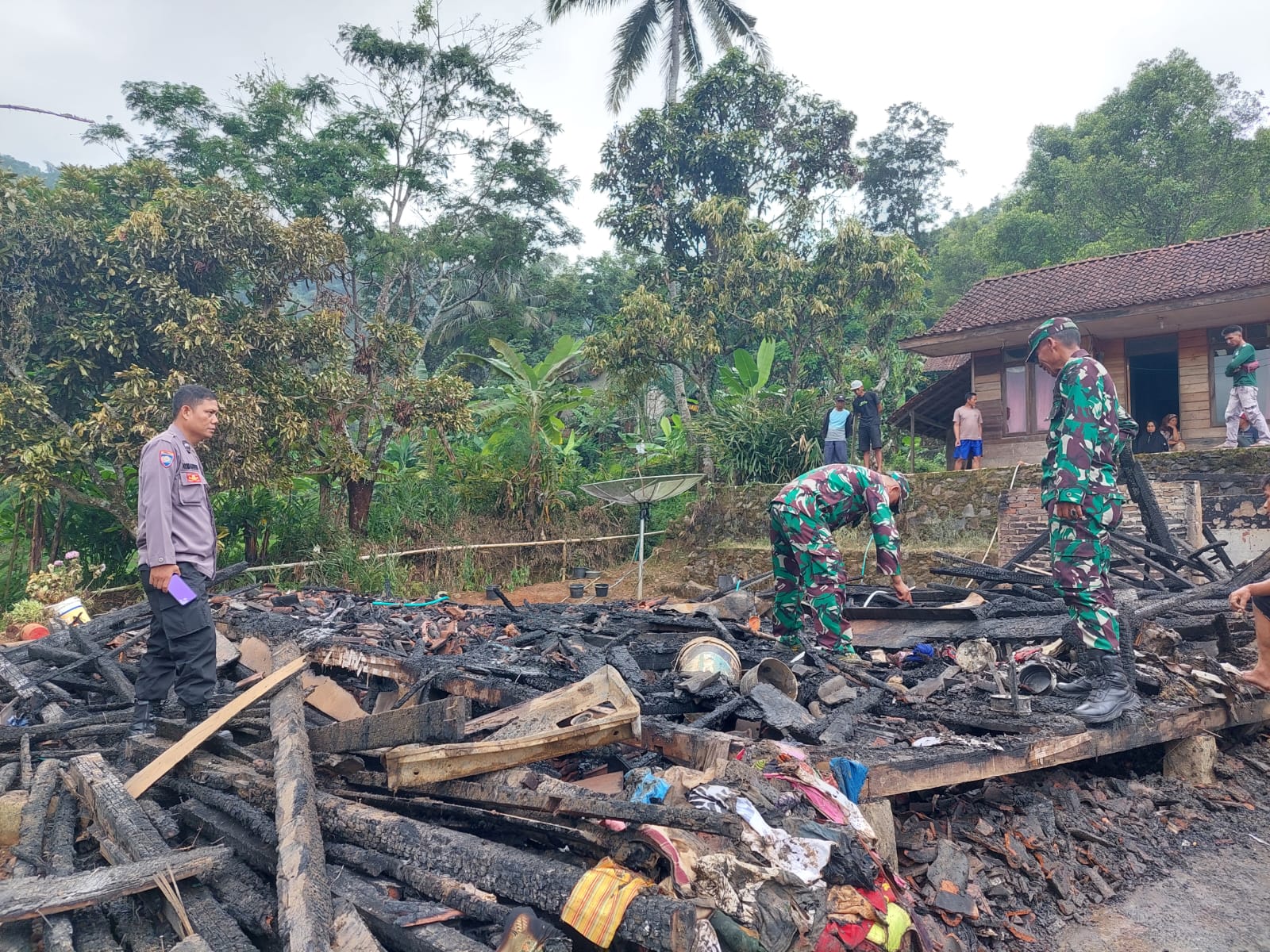 Kapolsek Cisompet, AKP Hilman Nugraha, bersama unsur TNI melakukan cek TKP dan membantu evakuasi rumah semi permanen yang terbakar di Kampung Cioray, Desa Panyindangan, Kecamatan Cisompet, Kabupaten Garut, Kamis (4/5/2023) (Foto: Istimewa)